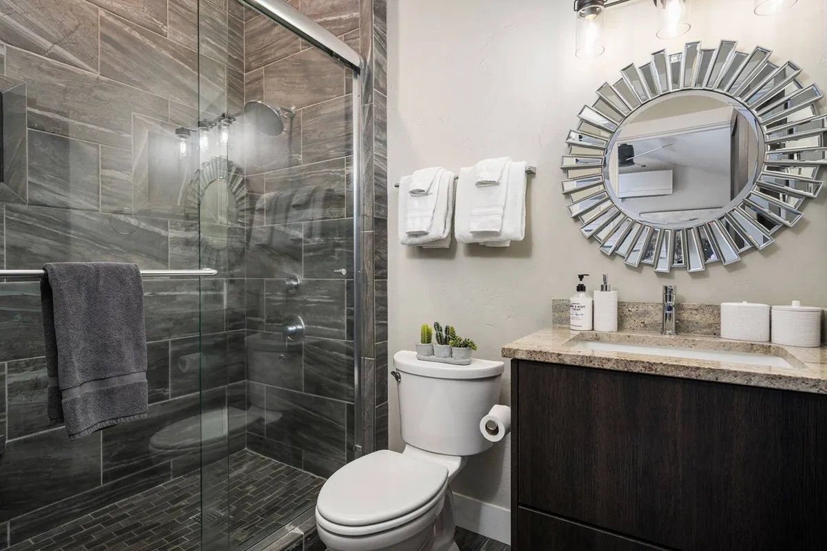 A serene bathroom with a walk-in shower, modern vanity sink, and large mirror. The area is designed for comfort and relaxation, offering a spa-like experience for guests.