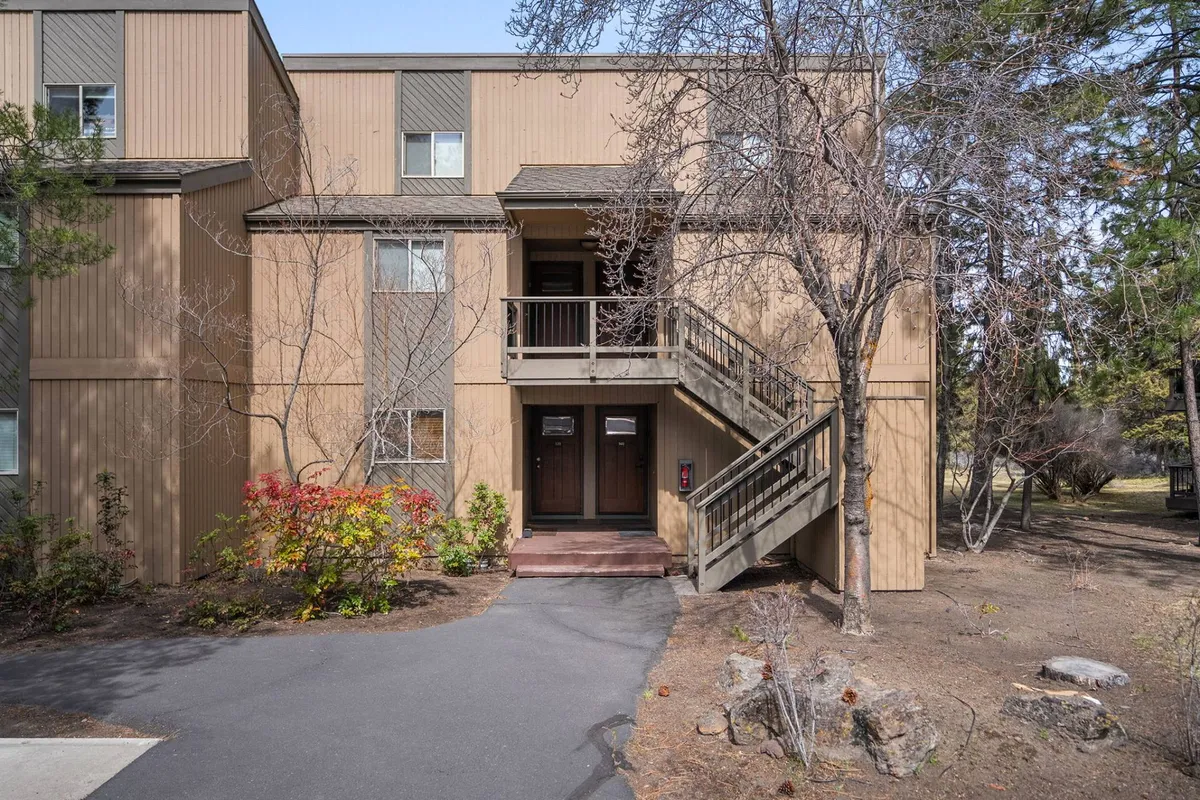 An inviting exterior view featuring entrance stairs, front doors, and lush landscaping. The scene evokes a welcoming atmosphere and hints at the communal aspects of the resort.