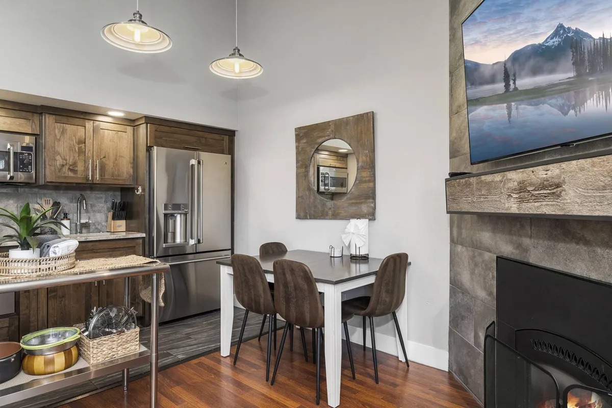 A welcoming living and dining area featuring a sofa, dining table, cabinetry, a mounted TV, and a fireplace. The layout supports cozy evenings watching movies or gathering around the fireplace for conversation.