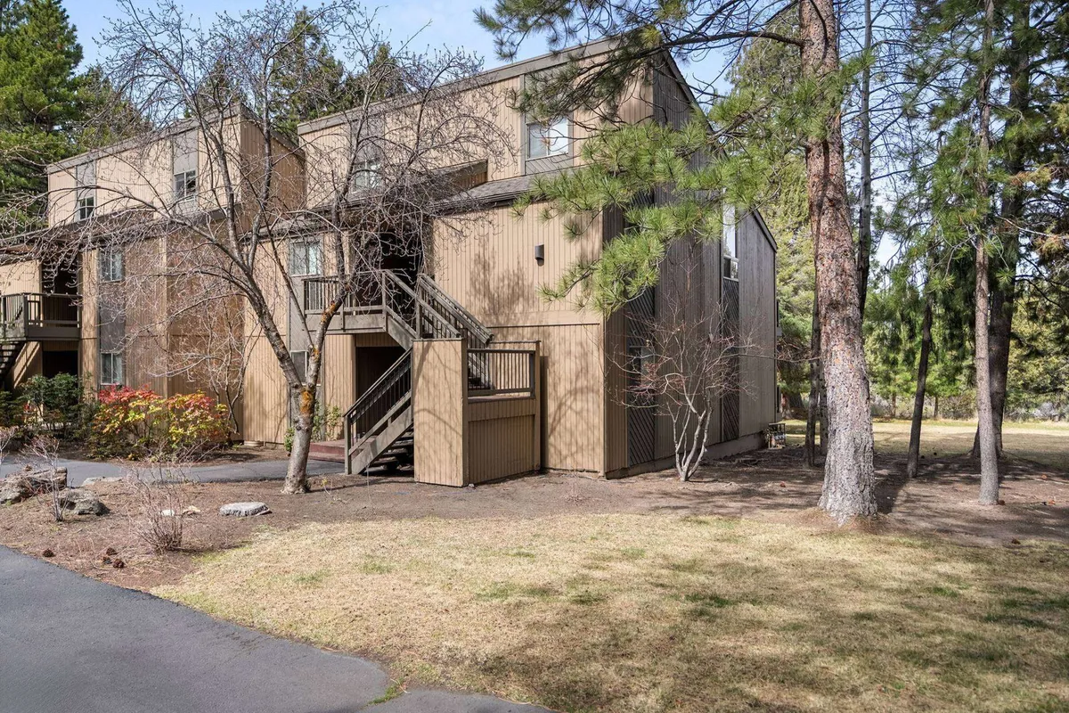 This exterior shot captures the wooden exterior of the condo surrounded by tall trees, with a staircase leading up to the entrance. The peaceful setting and natural landscaping convey a sense of privacy and immersion in nature.